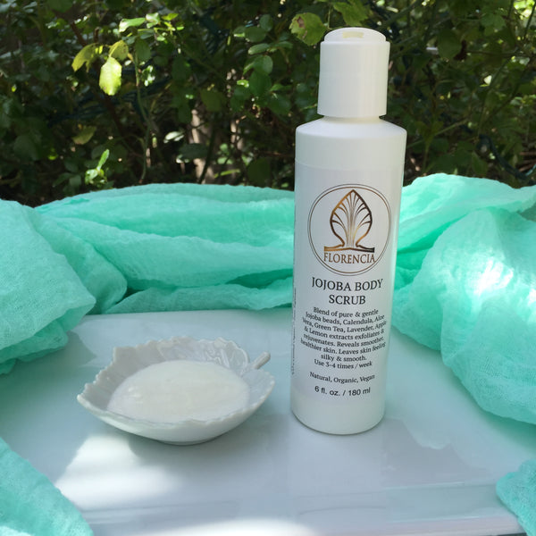 A Jojoba Body Scrub bottle with a white leaf dish on an outdoor table.